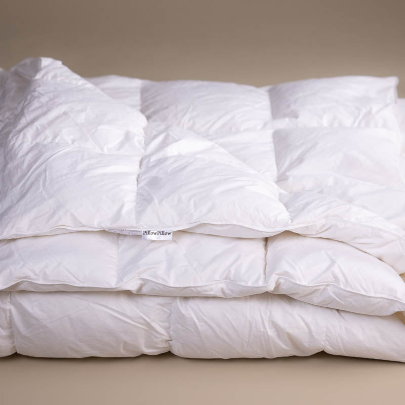 A 13.5 tog Goose Down and Feather Duvet, folded with a neutral bacground