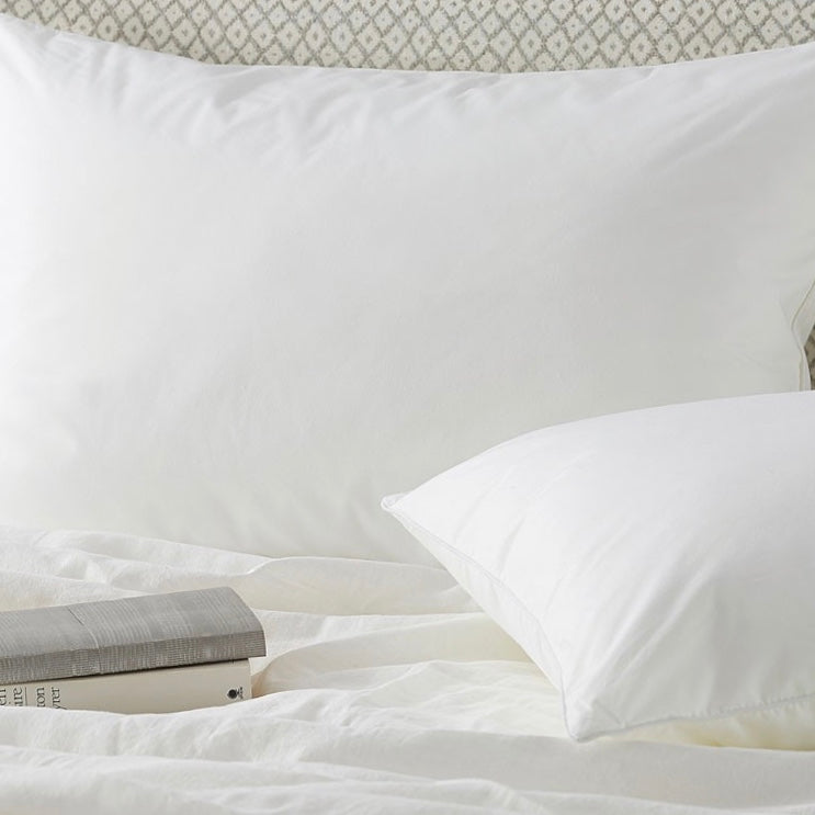 Pair of white pillows on a bed with books