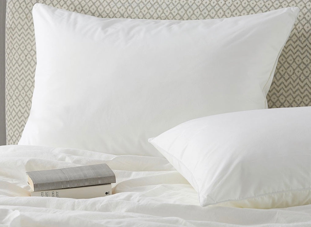 Pair of white pillows on a bed with books
